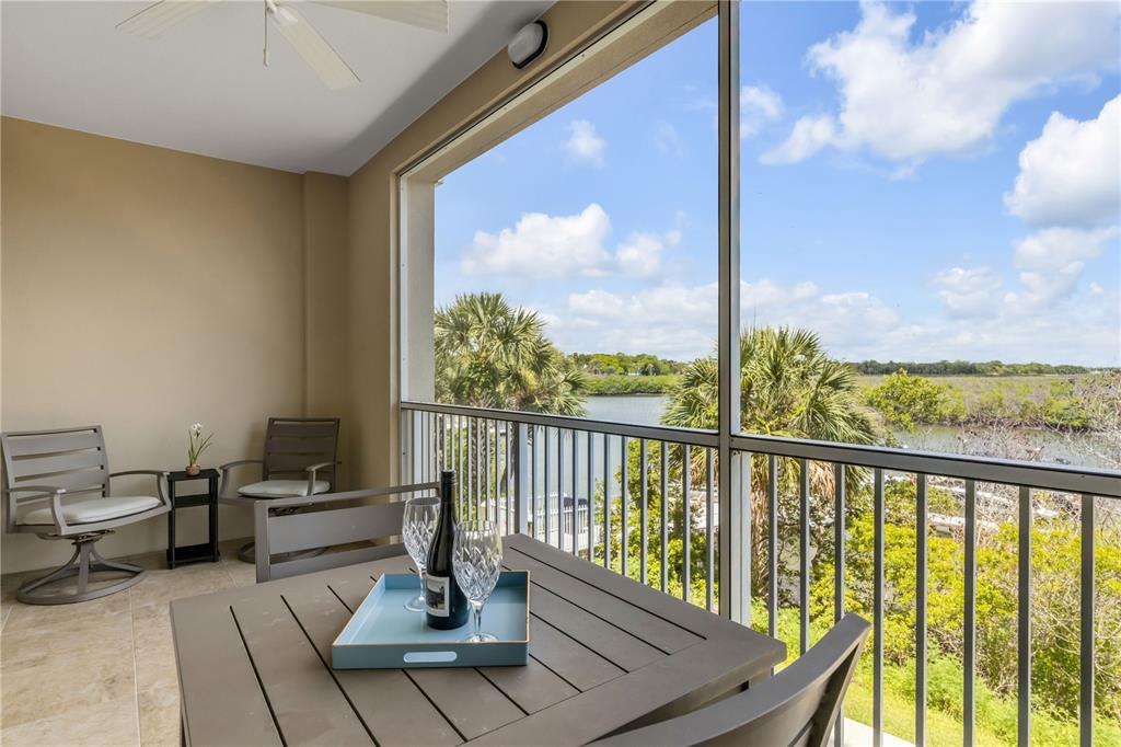 A screened-in balcony features a dining set and views of a waterway and trees — 5 RIVERWALK DRIVE UNIT 204, NEW SMYRNA BEACH, FL
