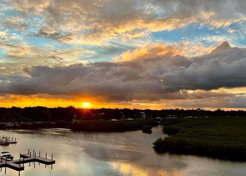 A sunset view over a river with a wooden dock and marshy banks — 5 RIVERWALK DRIVE UNIT 204, NEW SMYRNA BEACH, FL