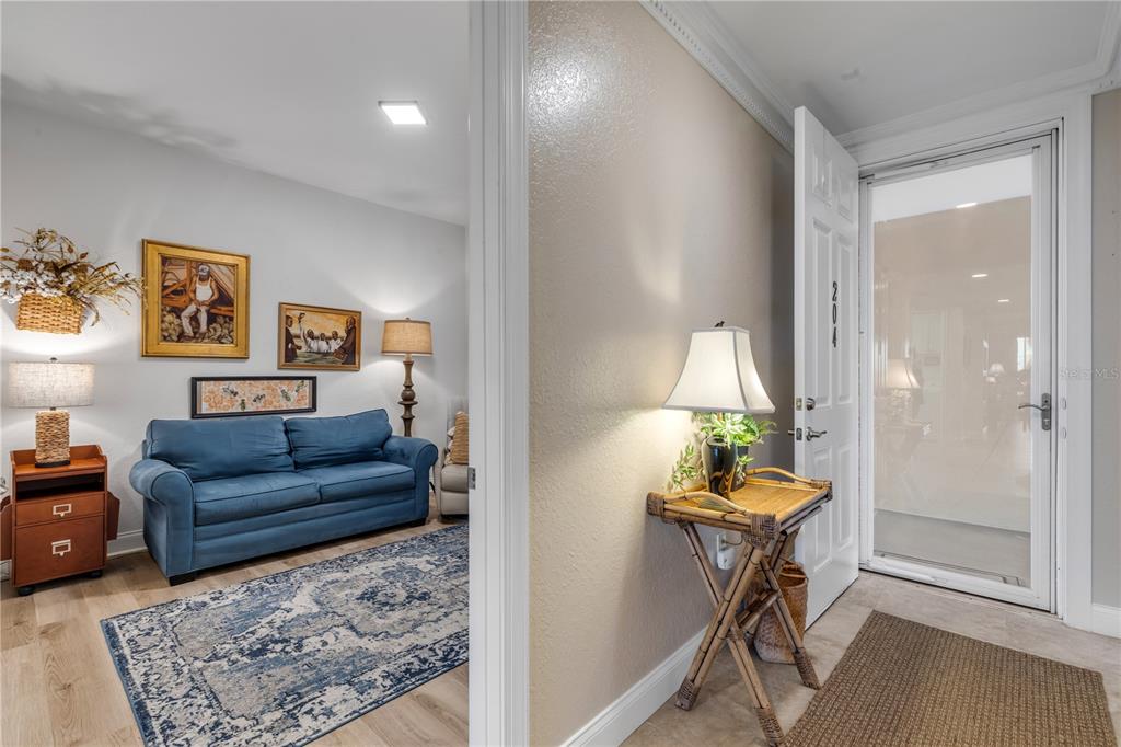 An entryway leads into a living room with a blue sofa and a patterned rug — 5 RIVERWALK DRIVE UNIT 204, NEW SMYRNA BEACH, FL