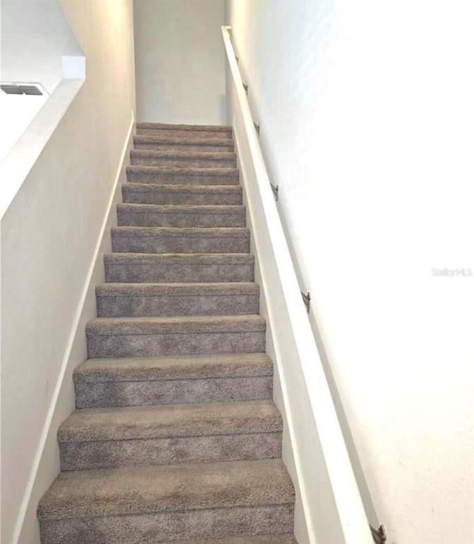 A straight staircase with gray carpet and a white handrail leads to a landing — 1128 MERRILL STREET, DAVENPORT, FL