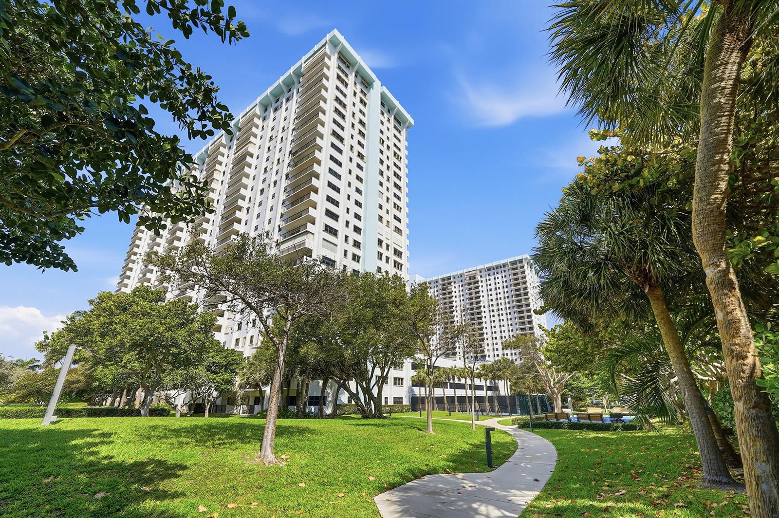 A paved path leads through a grassy park toward two tall residential apartment buildings — 1201 S Ocean Drive # 506s, Hollywood FL 33019, HOLLYWOOD, FL