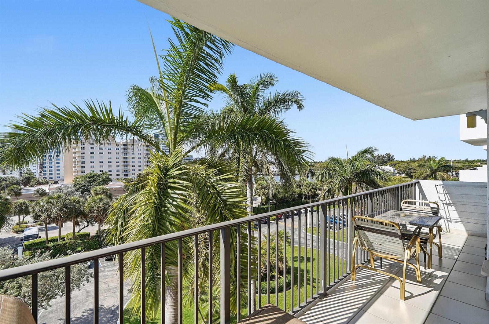 A balcony with a metal railing, outdoor furniture, and a view of palm trees — 1201 S Ocean Drive # 506s, Hollywood FL 33019, HOLLYWOOD, FL