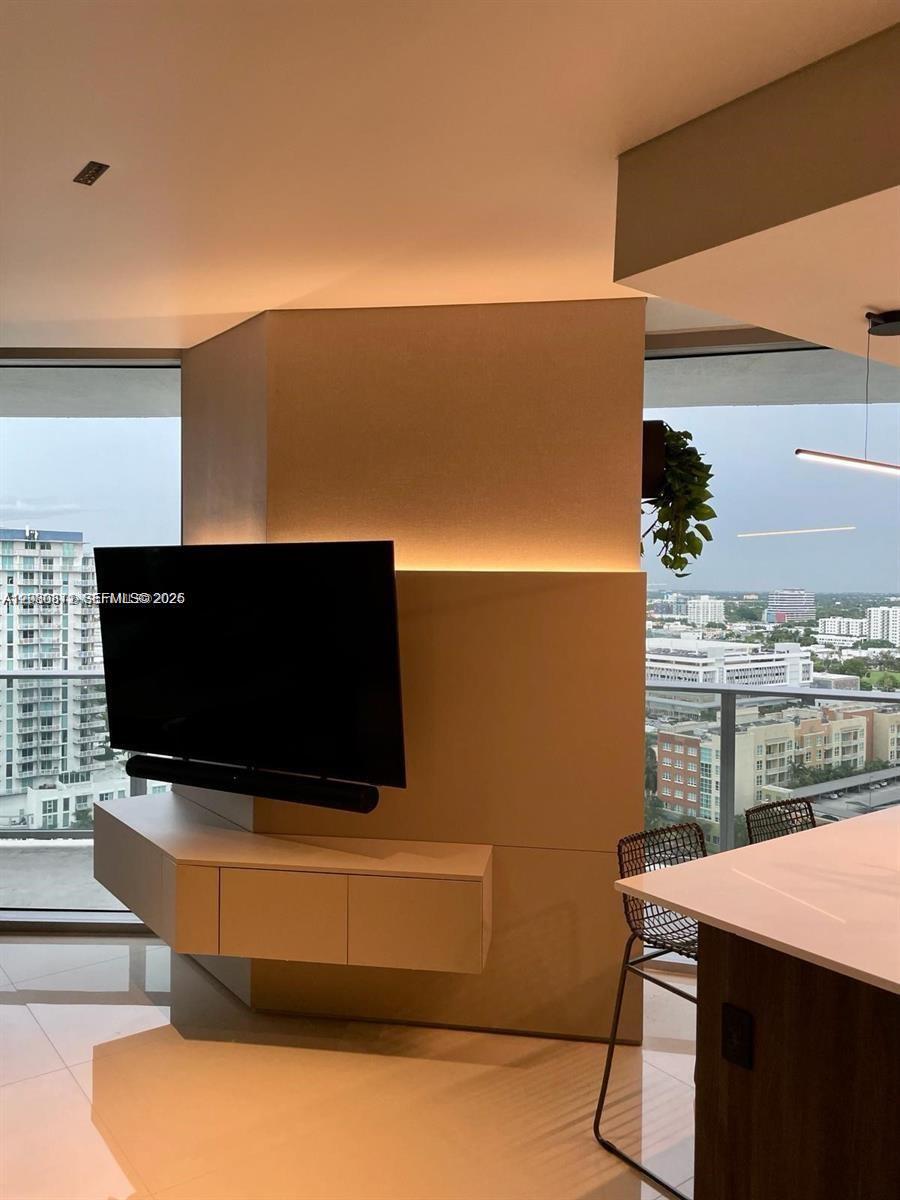 A modern living area features a wall-mounted television, built-in cabinetry, and floor-to-ceiling windows — 488 NE 18th St # 1901, Miami FL 33132, MIAMI, FL