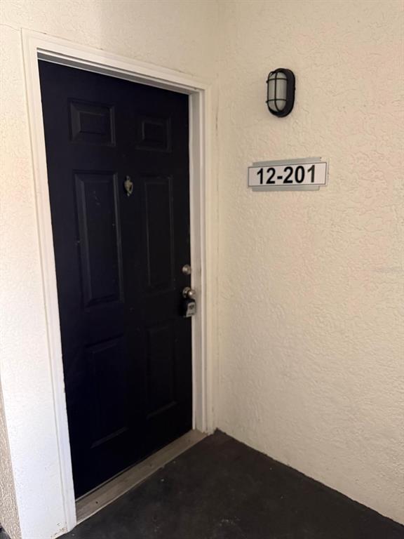 A dark-colored front door with a lockbox is situated next to a unit number sign — 2537 MAITLAND CROSSING WAY UNIT 12-201, ORLANDO, FL