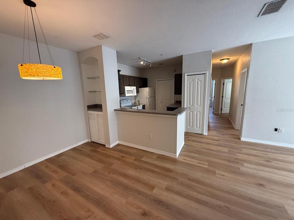 An open-concept living area features wood-look flooring, a kitchen with a breakfast bar, and shelving — 2537 MAITLAND CROSSING WAY UNIT 12-201, ORLANDO, FL