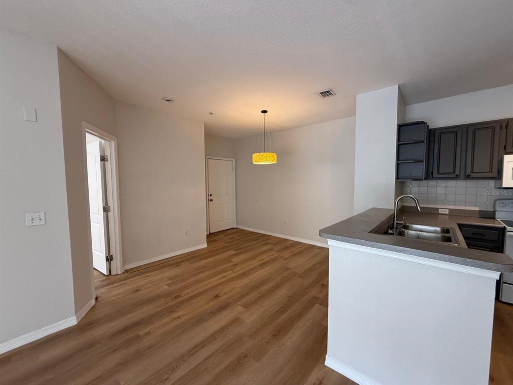An open-concept dining area features wood-look flooring, a pendant light, and an adjacent kitchen — 2537 MAITLAND CROSSING WAY UNIT 12-201, ORLANDO, FL