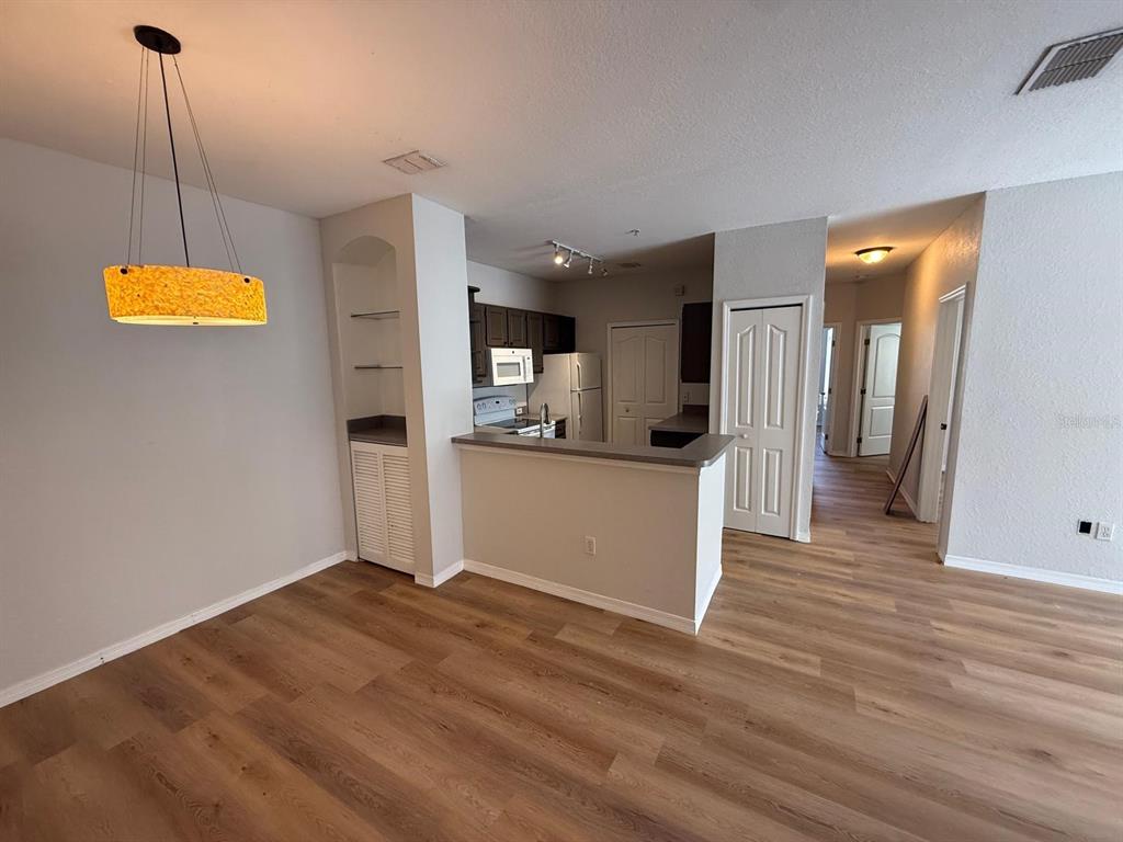 A view of a dining area and kitchen with wood-look flooring and a breakfast bar — 2537 MAITLAND CROSSING WAY UNIT 12-201, ORLANDO, FL