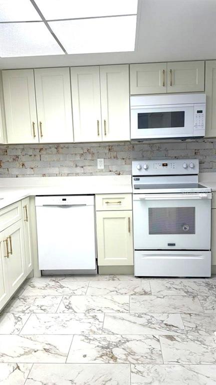 A kitchen features white cabinets, a white stove and dishwasher, and marble-patterned tile flooring — 610 INDIAN ROCKS ROAD N UNIT 103, BELLEAIR BLUFFS, FL