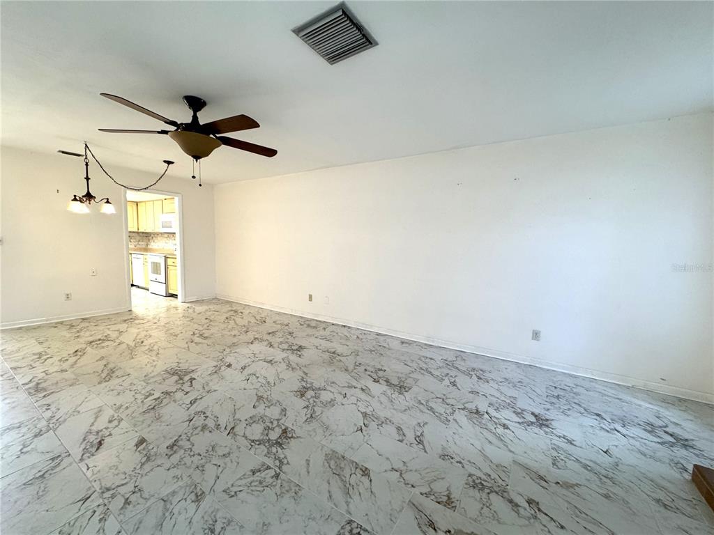 A living room with white walls, marble-patterned tile flooring, and a ceiling fan — 610 INDIAN ROCKS ROAD N UNIT 103, BELLEAIR BLUFFS, FL