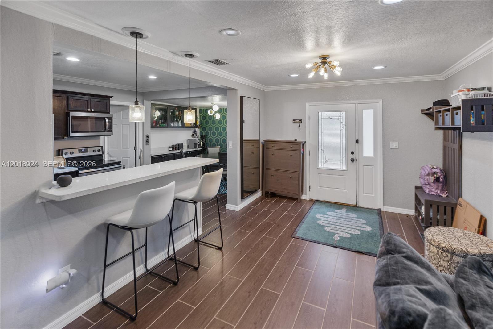 A kitchen with a breakfast bar opens into an entryway featuring a front door — ORLANDO, FL