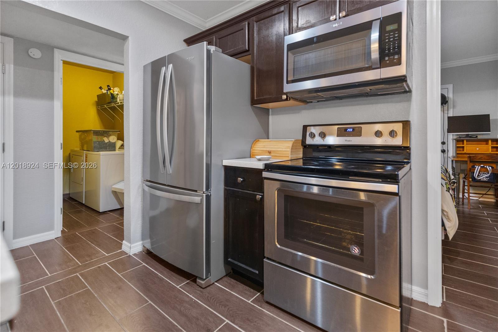A kitchen features dark wood cabinets, stainless steel appliances, and brown tile flooring — ORLANDO, FL