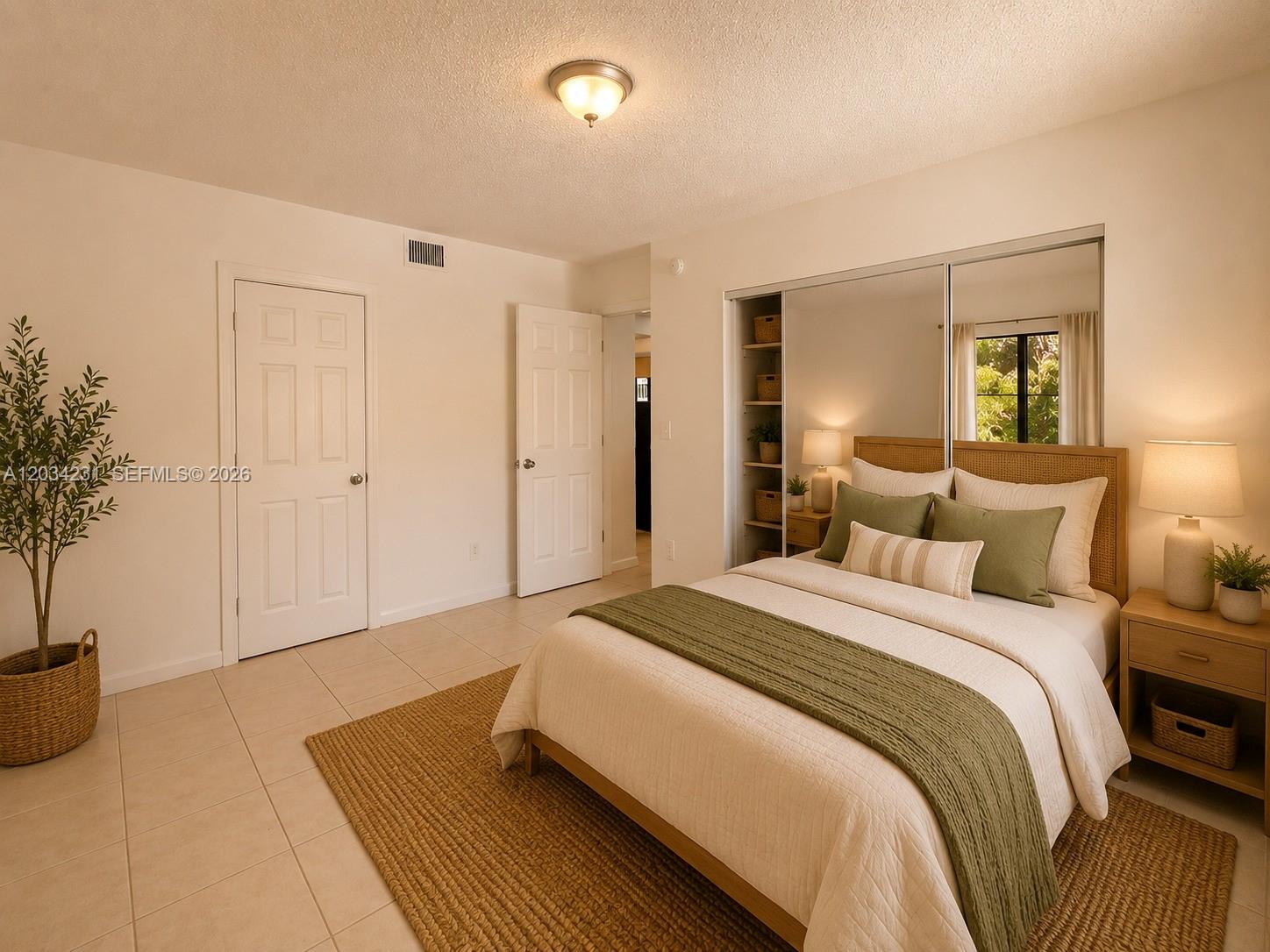 A bedroom features a bed with green bedding, tiled floors, and mirrored closet doors — 2775 W 61st St # 102, Hialeah FL 33016, HIALEAH, FL