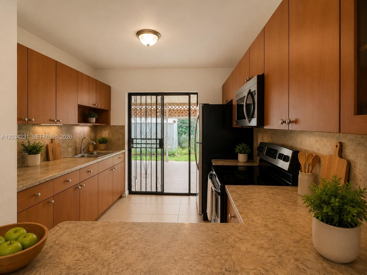 A galley kitchen features wood cabinets, laminate countertops, black appliances, and a sliding glass door — 2775 W 61st St # 102, Hialeah FL 33016, HIALEAH, FL