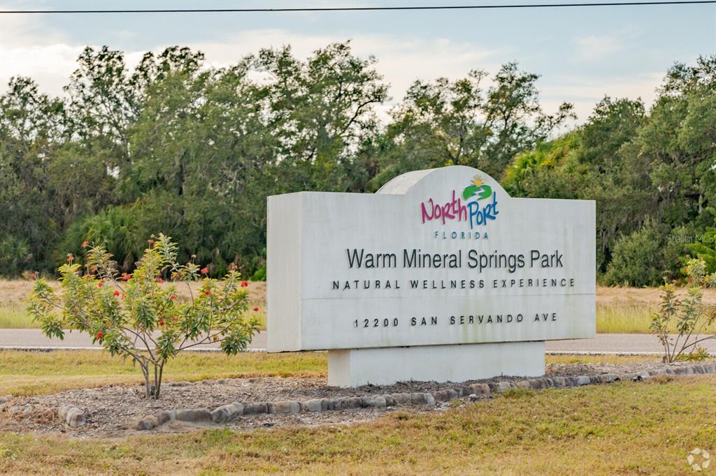A sign for Warm Mineral Springs Park stands in a grassy area with trees behind it — SAN RAFAEL AVENUE, NORTH PORT, FL