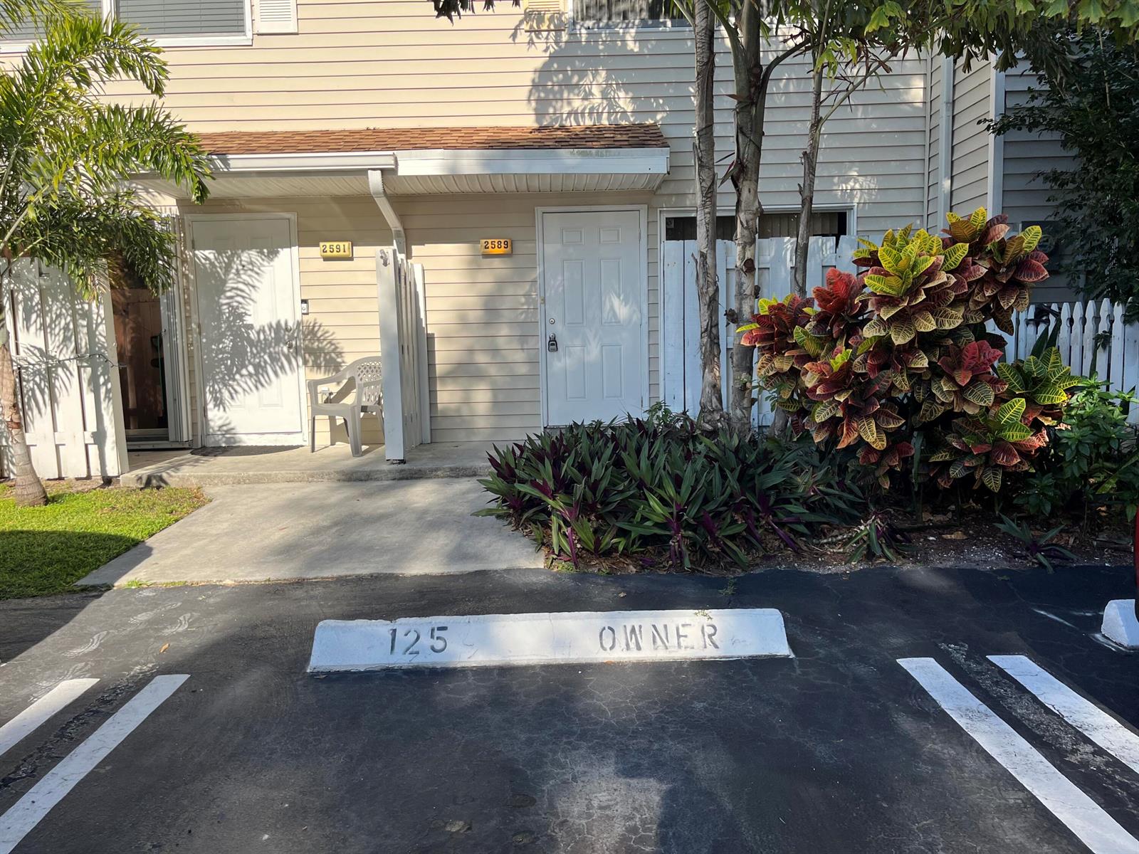 A parking space marked 125 OWNER sits in front of two residential units with numbered doors — 2589 NE 15th Street, Pompano Beach FL 33062, POMPANO BEACH, FL