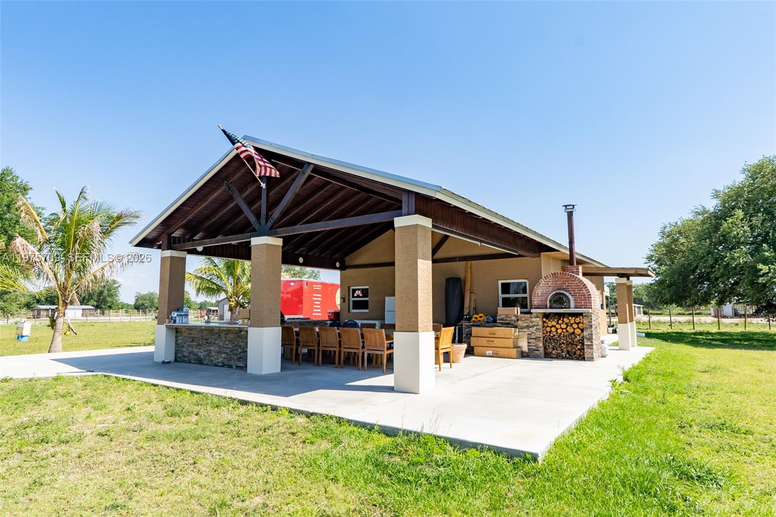 An outdoor covered patio features a stone bar, dining area, and a brick pizza oven — 21810 NW 270TH ST, Okeechobee FL 34972, OKEECHOBEE, FL