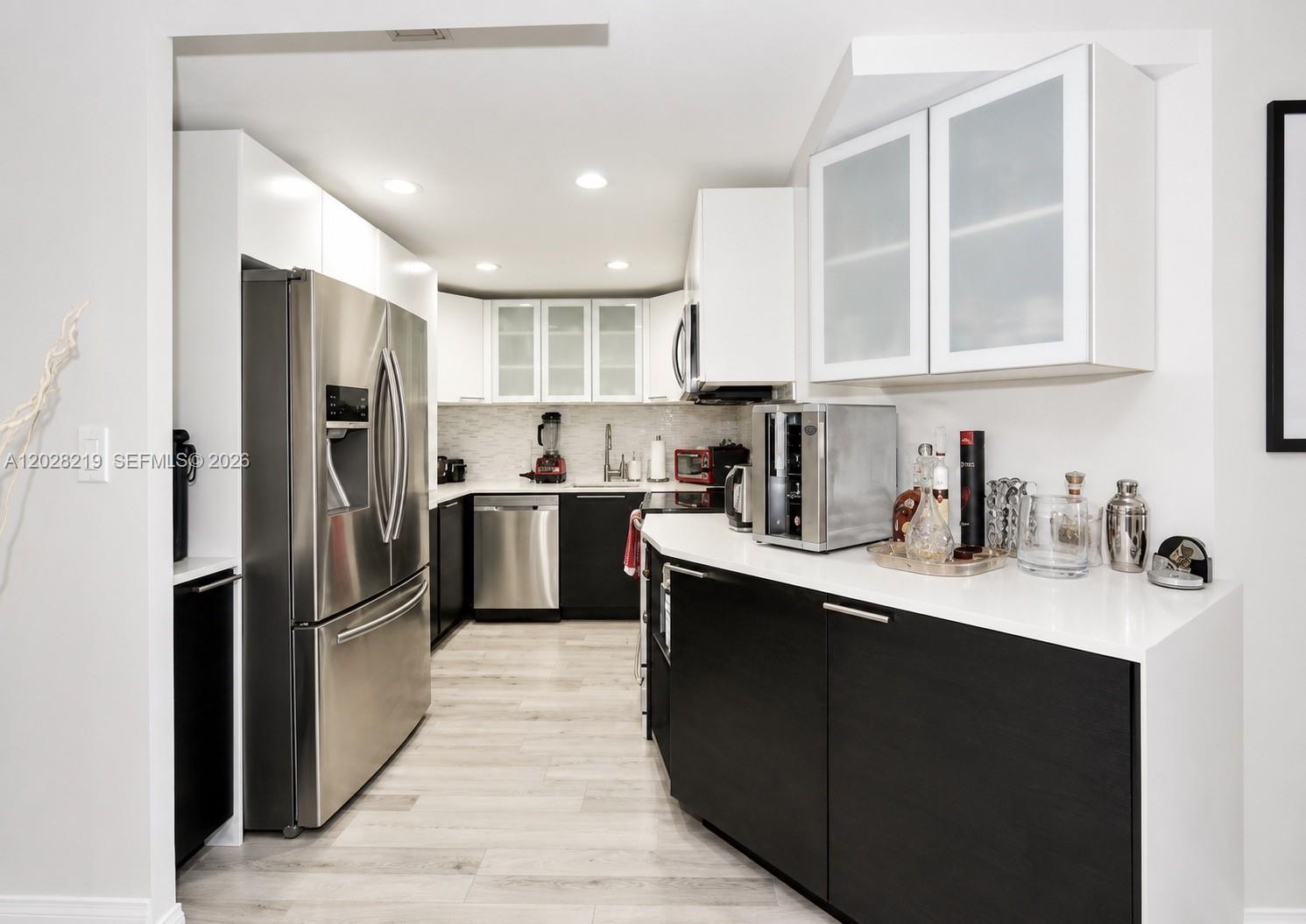 A modern kitchen features black lower cabinets, white upper cabinets, stainless steel appliances, and countertops — 2500 Parkview Dr # 1815, Hallandale Beach FL 33009, HALLANDALE BEACH, FL