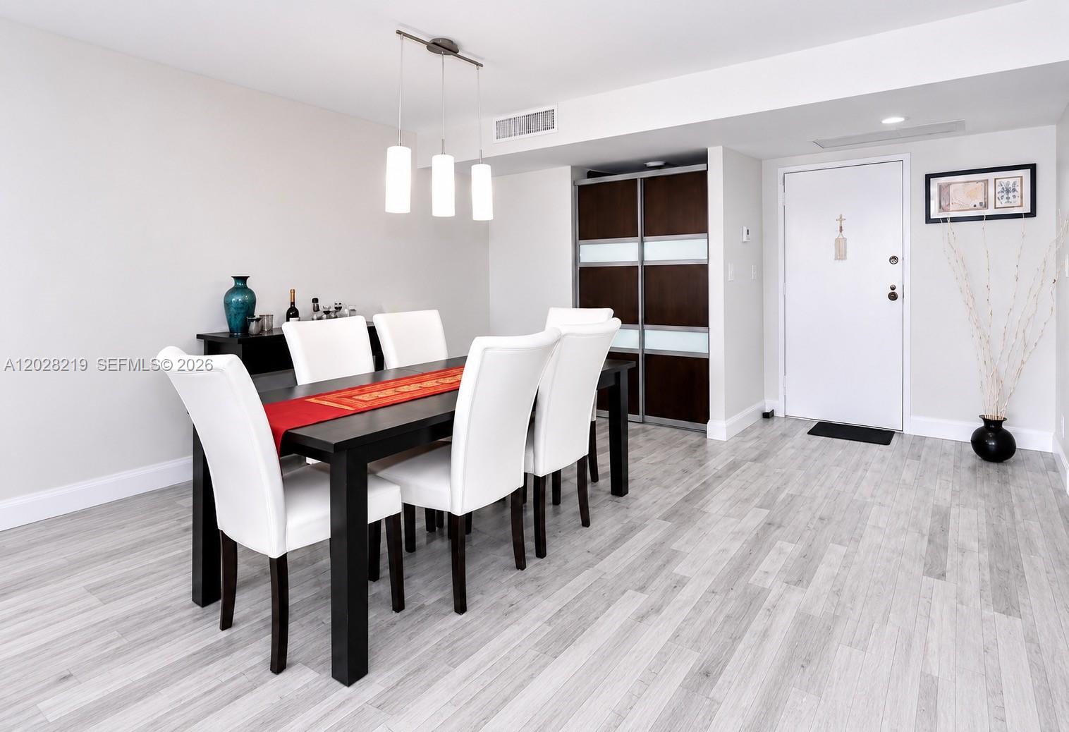 A dining room features a dark table with white chairs, pendant lights, and light flooring — 2500 Parkview Dr # 1815, Hallandale Beach FL 33009, HALLANDALE BEACH, FL