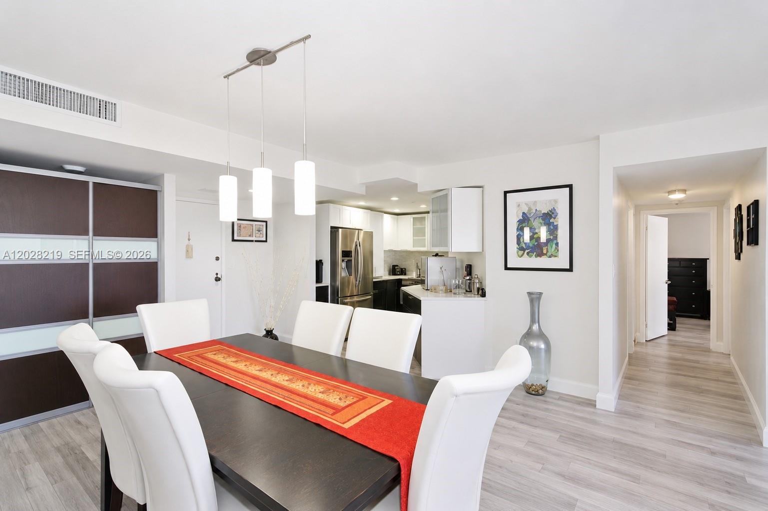 A dining area with a dark table and white chairs sits adjacent to a kitchen — 2500 Parkview Dr # 1815, Hallandale Beach FL 33009, HALLANDALE BEACH, FL