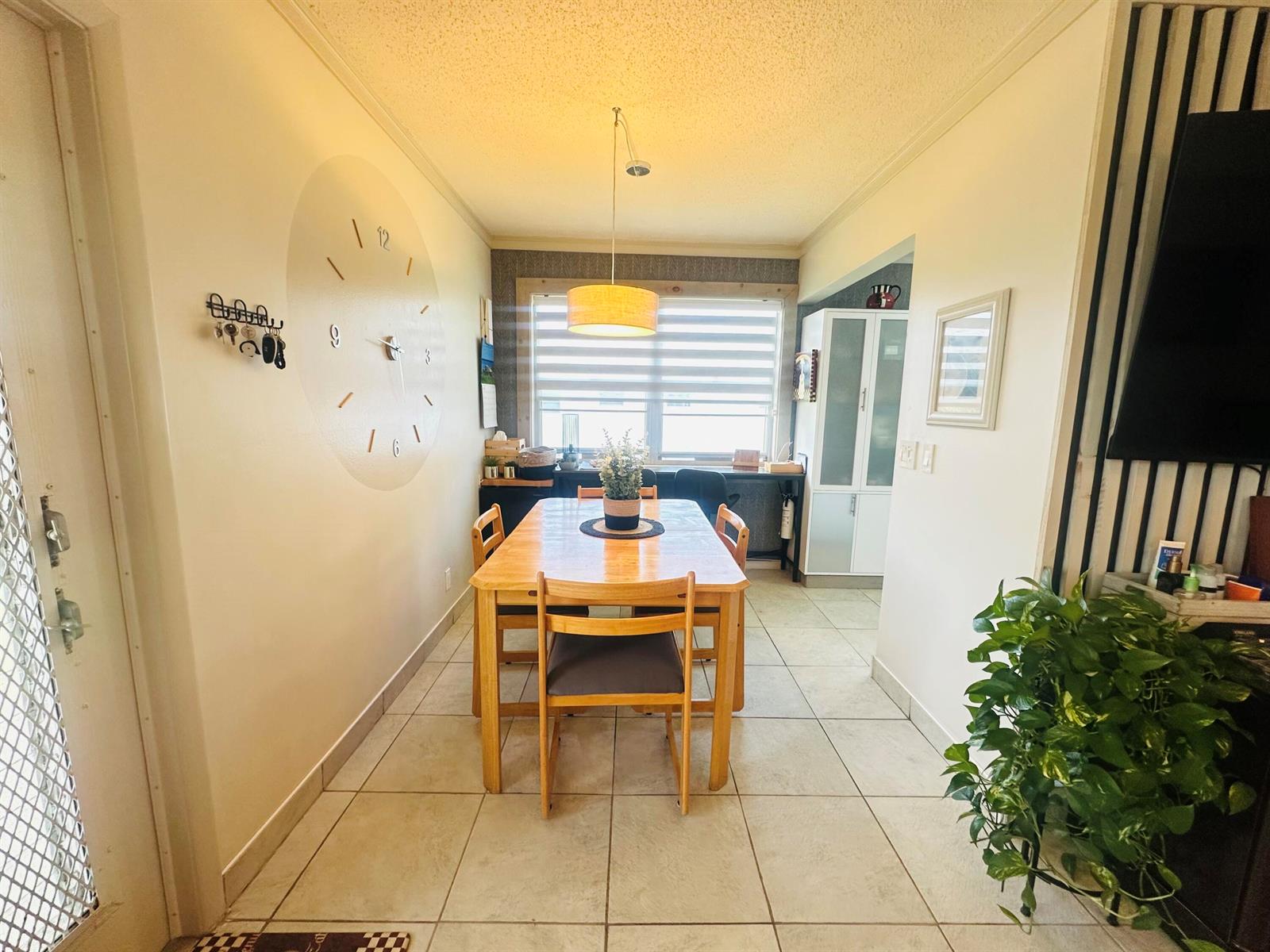 A dining room features a wooden table, a large wall clock, and tile flooring — 200 Ventnor L # 200, Deerfield Beach FL 33442, DEERFIELD BEACH, FL