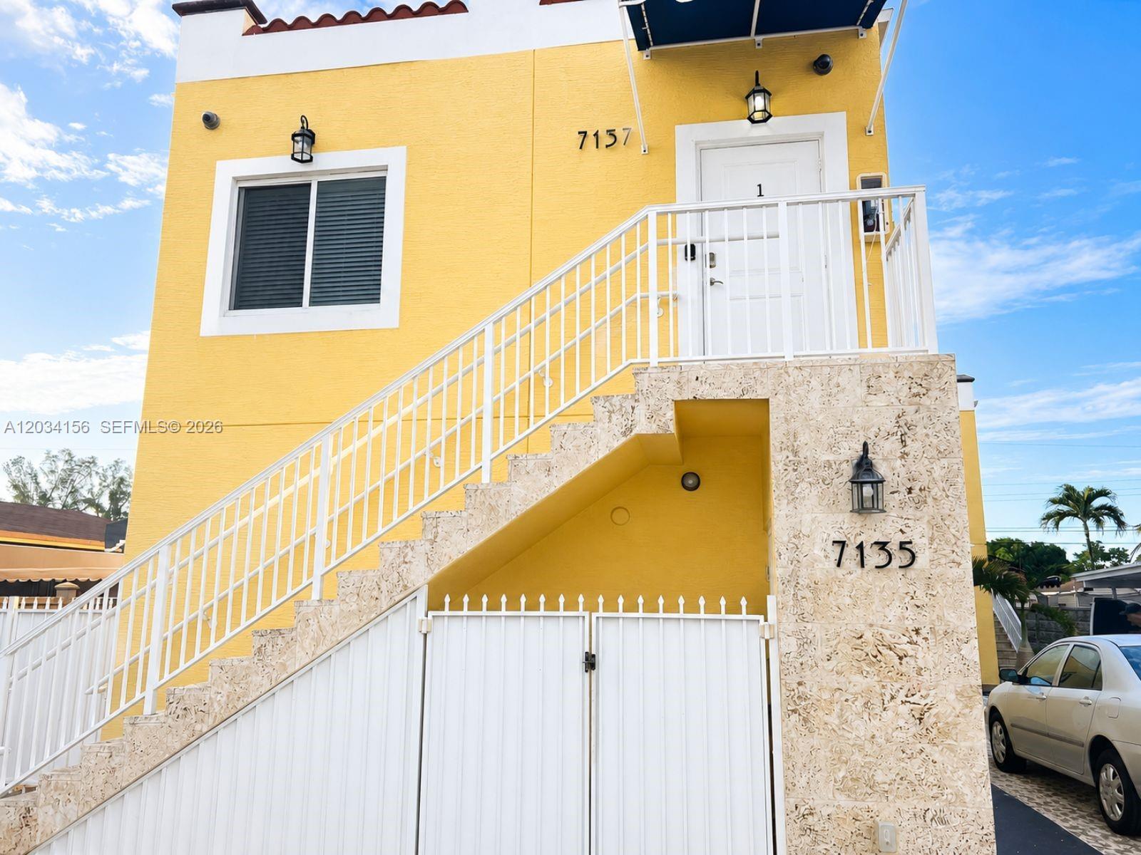 A yellow two-story building features an exterior staircase leading to an upper-level entrance — 7135 SW 21st St # 1, Miami FL 33155, MIAMI, FL