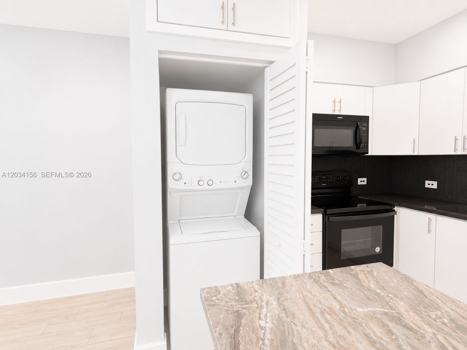 A kitchen features white cabinetry, black appliances, a stone countertop, and a stacked laundry unit — 7135 SW 21st St # 1, Miami FL 33155, MIAMI, FL
