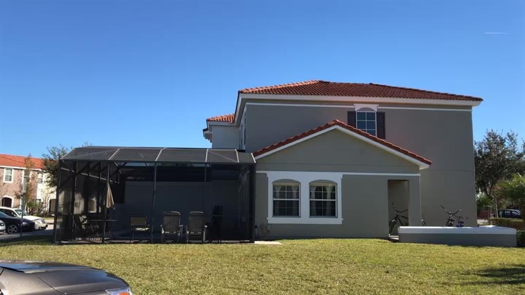 A two-story house with a screened-in patio and a tiled roof sits on a lawn — 4523 ALBERTO CIRCLE, KISSIMMEE, FL