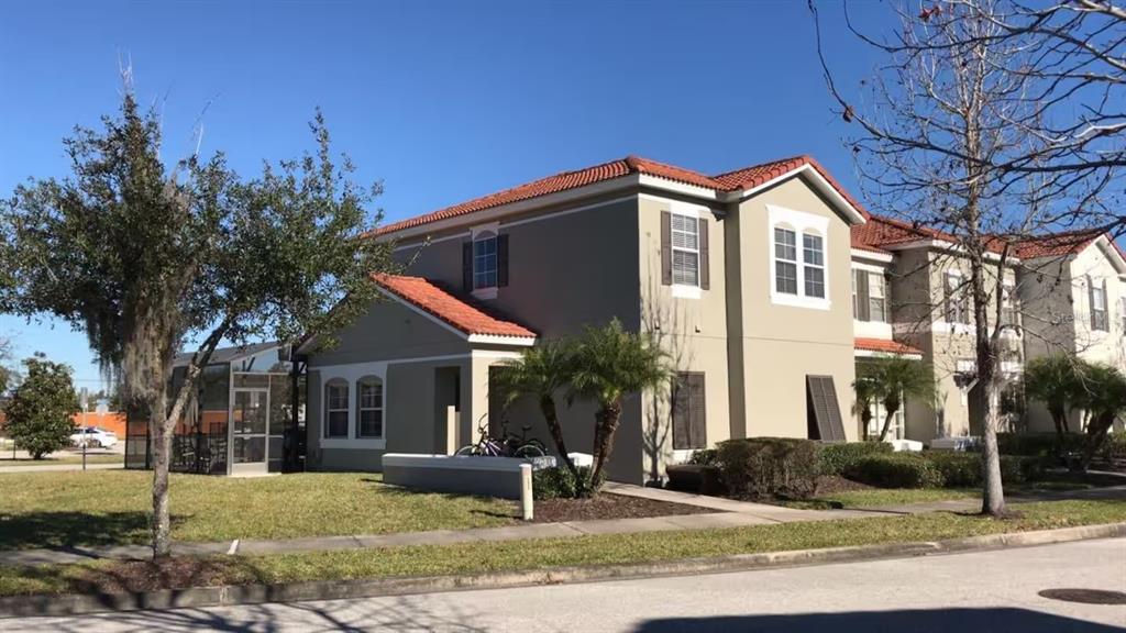 A two-story tan stucco townhouse with a red tile roof and a screened-in patio — 4523 ALBERTO CIRCLE, KISSIMMEE, FL