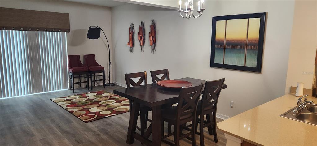 A dining area features a dark wood table, chairs, a patterned rug, and wall art — 4546 ALBERTO CIRCLE, KISSIMMEE, FL