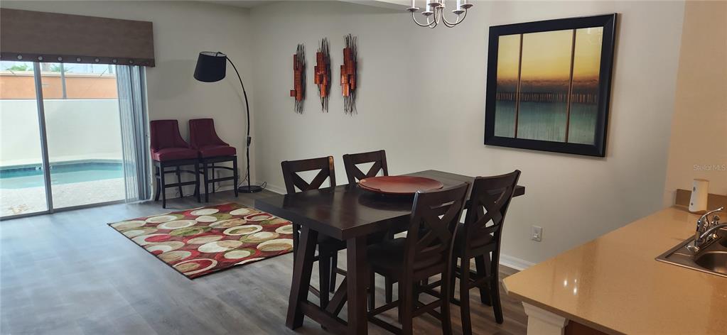 A dining area features a dark wood table, chairs, a patterned rug, and pool views — 4546 ALBERTO CIRCLE, KISSIMMEE, FL