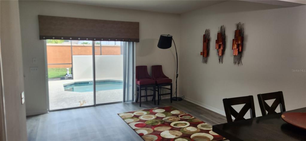 A dining area with a patterned rug, two red chairs, and a sliding door to a pool — 4546 ALBERTO CIRCLE, KISSIMMEE, FL
