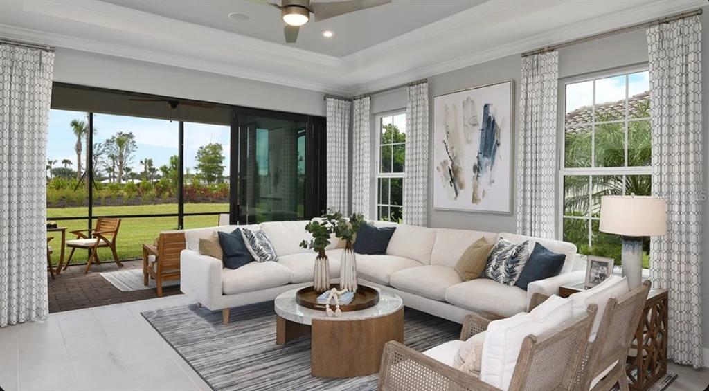 A bright living room features a white sectional, two armchairs, and an open-concept kitchen — 13320 SANTINI CIRCLE, ENGLEWOOD, FL