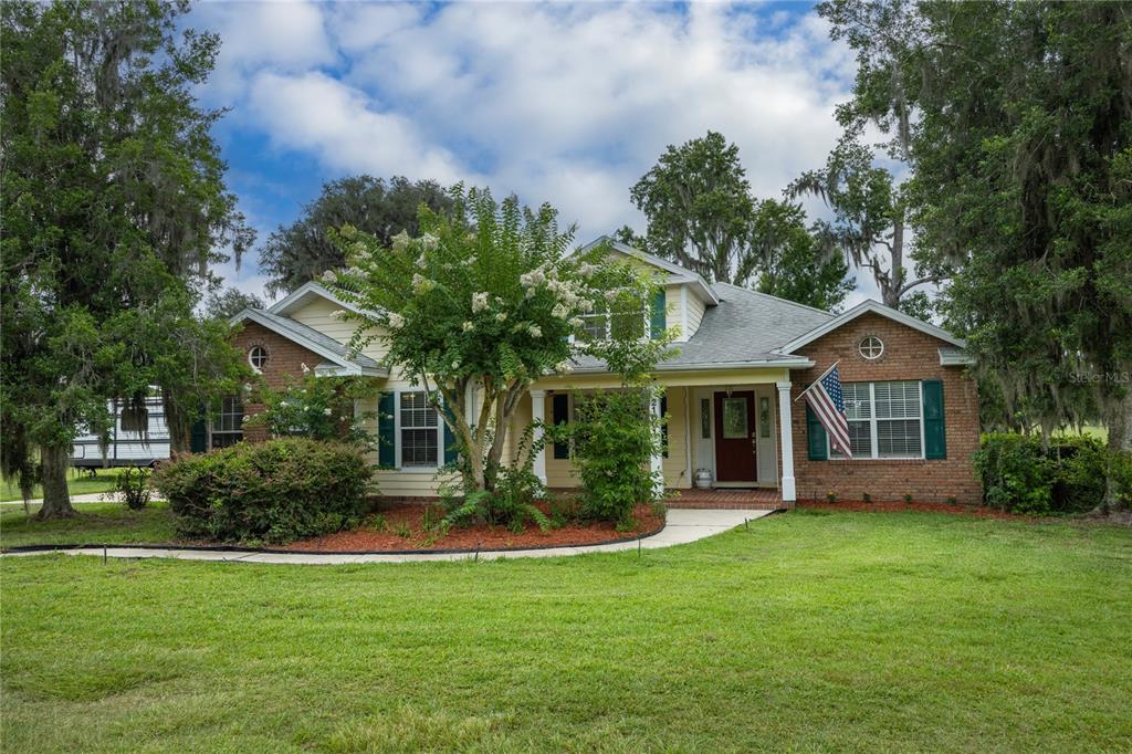 A single-story house with a brick and siding exterior, a front porch, and mature trees — 21601 OLD BELLAMY ROAD, ALACHUA, FL
