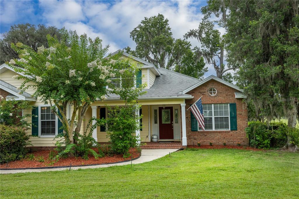 A single-story house with yellow siding, a brick facade, and a covered front porch — 21601 OLD BELLAMY ROAD, ALACHUA, FL