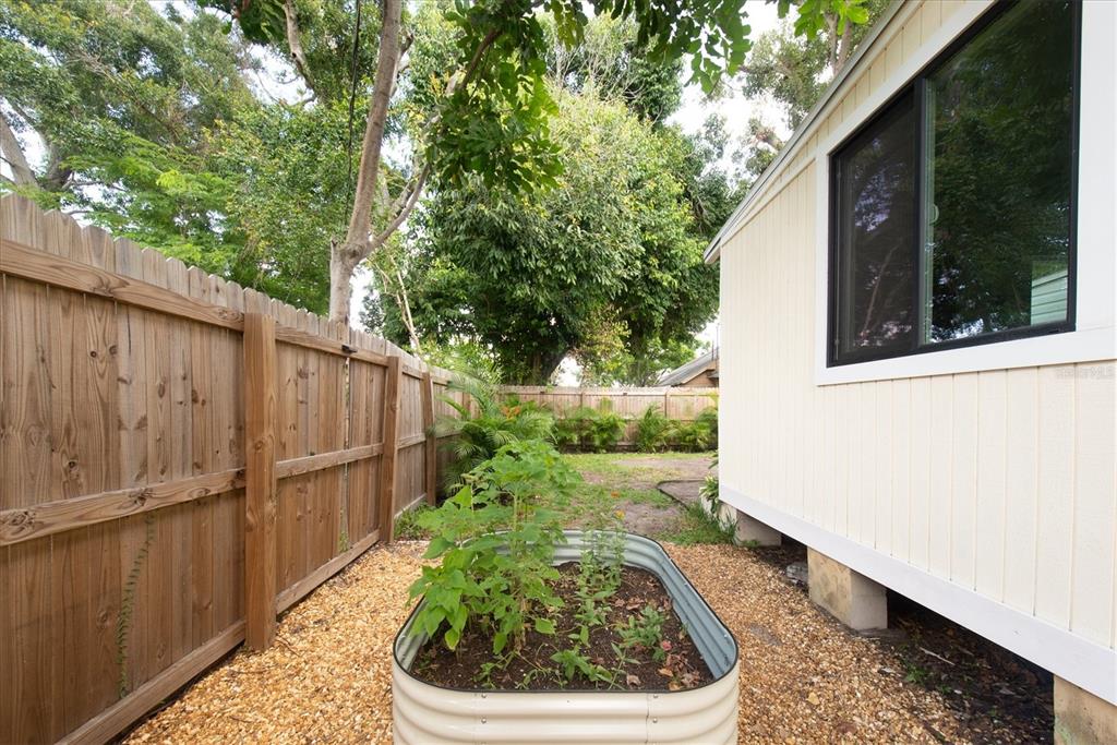 A side yard features a metal raised garden bed, gravel ground cover, and a wooden fence — 1840 51ST STREET S, GULFPORT, FL