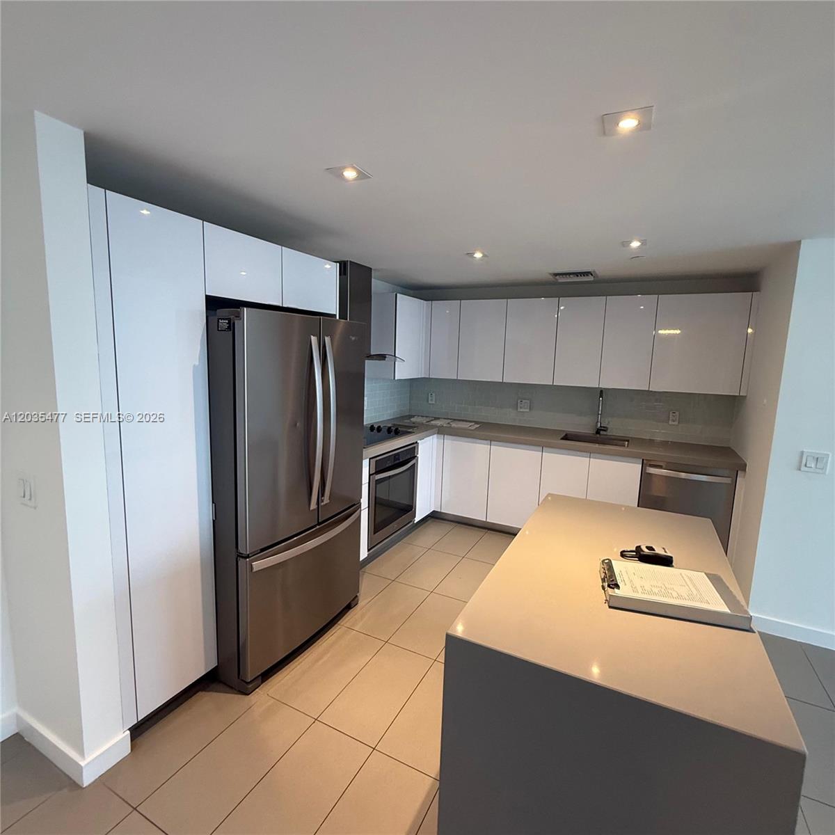 A modern kitchen features white cabinets, stainless steel appliances, and a gray island countertop — 1600 NE 1st Ave # 2607, Miami FL 33132, MIAMI, FL