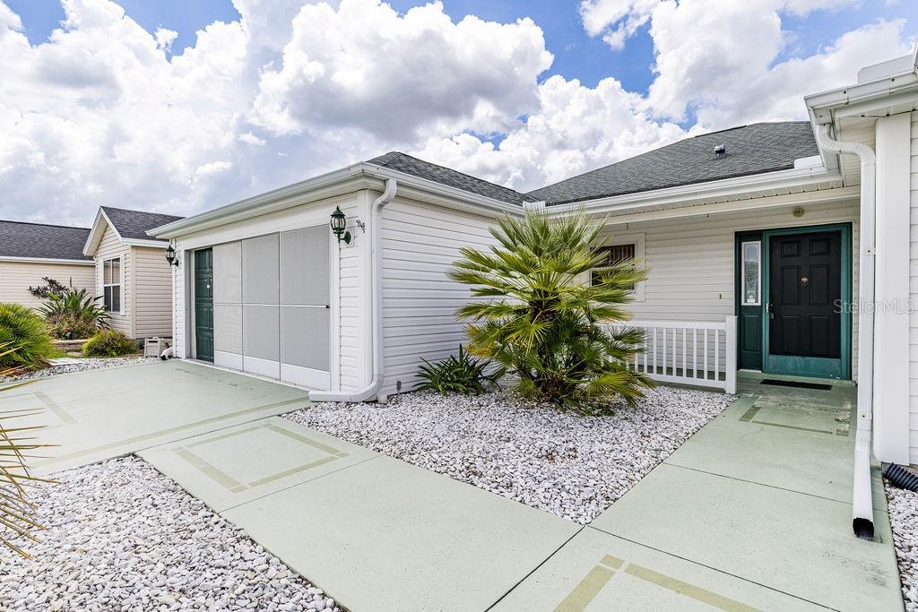A white-sided house with a garage, a palm tree, and a green front door — 814 SANTA RITA WAY, THE VILLAGES, FL
