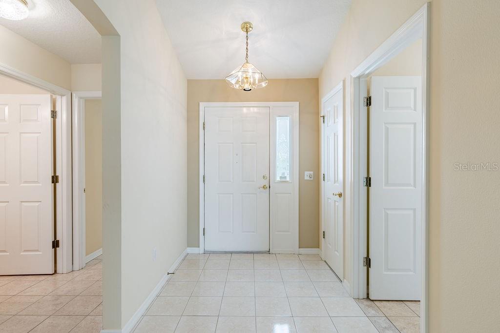 An entryway features a white front door, tiled flooring, and a hanging light fixture — 814 SANTA RITA WAY, THE VILLAGES, FL