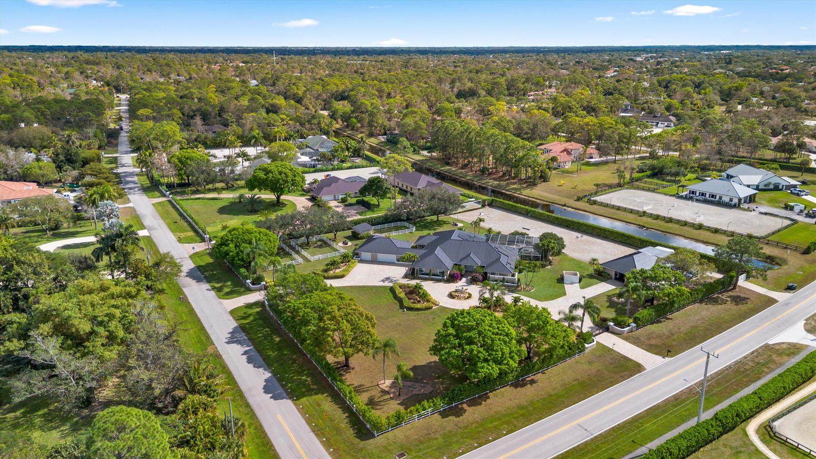 An aerial view shows a residential property with a large house, pool, and horse arena — 14868 Paddock Drive, Wellington FL 33414, WELLINGTON, FL