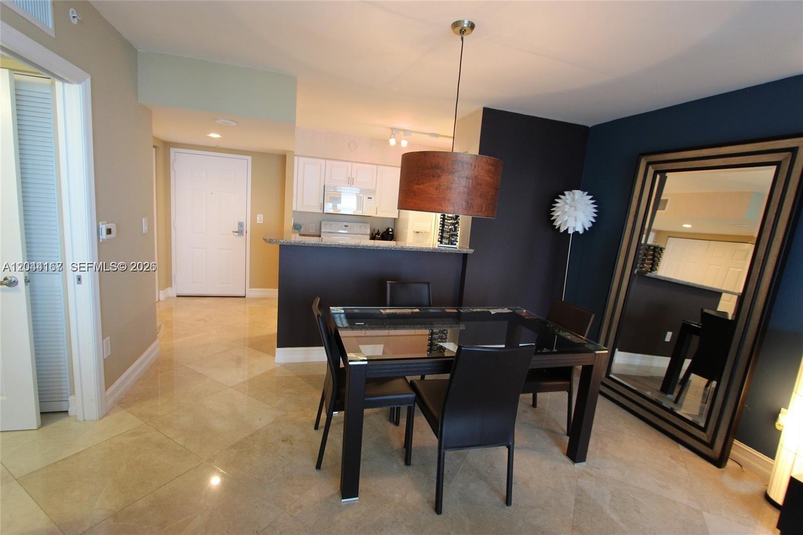 A dining area with a glass table and dark chairs sits before a kitchen counter — 1155 Brickell Bay Dr # 3107, Miami FL 33131, MIAMI, FL