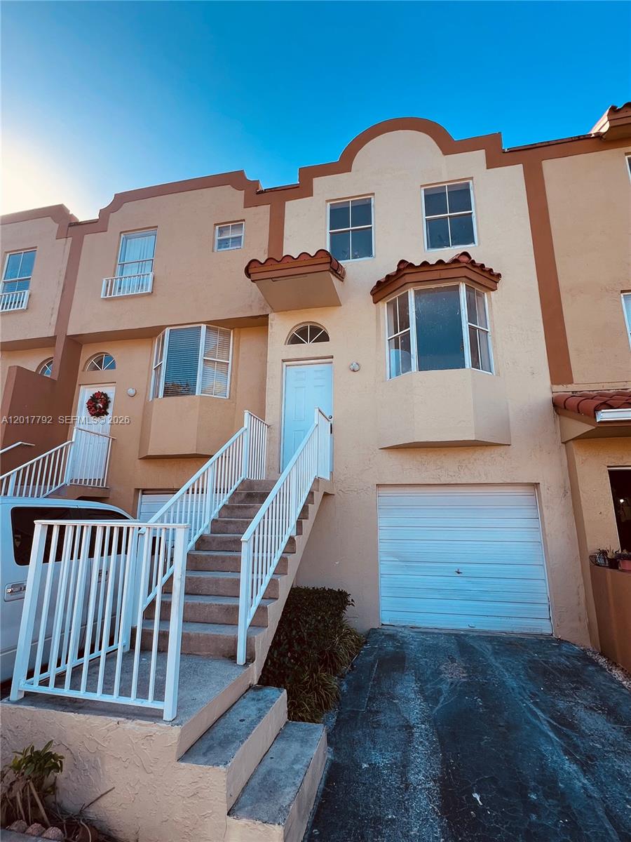 A multi-story townhouse exterior features a white front door, a garage, and an outdoor staircase — 380 NW 85th Pl # 1406, Miami FL 33126, MIAMI, FL
