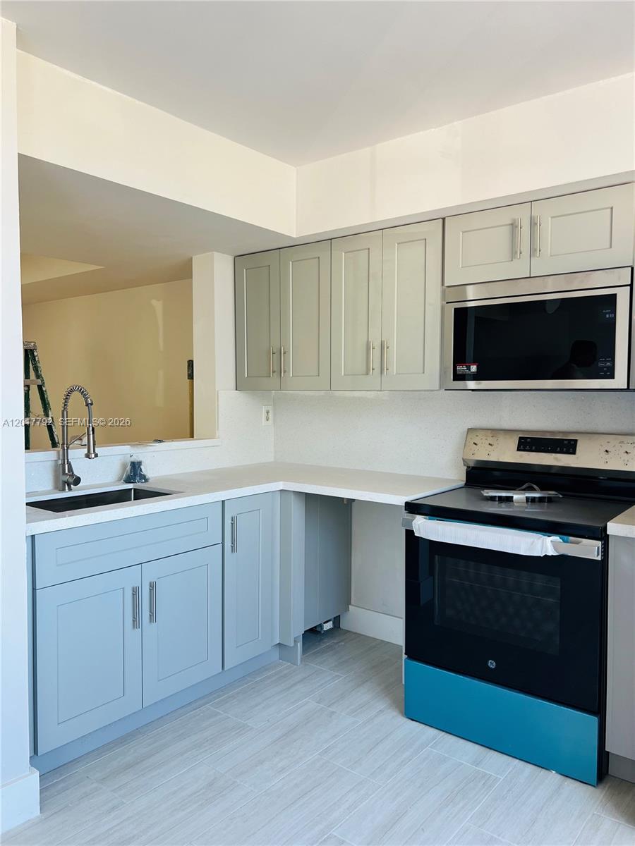 A kitchen features light blue lower cabinets, gray upper cabinets, and a black oven — 380 NW 85th Pl # 1406, Miami FL 33126, MIAMI, FL
