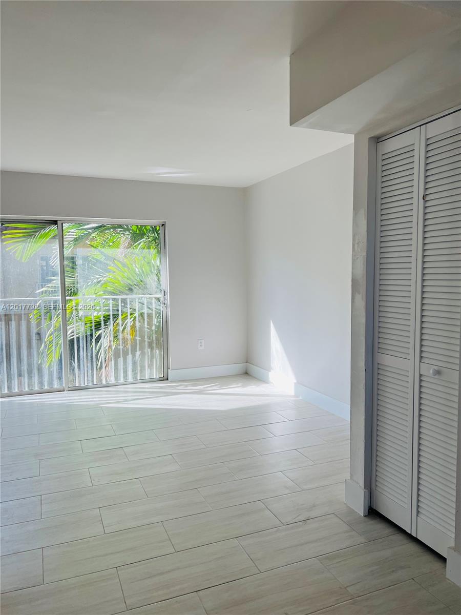 A bright room features light-colored tile flooring, a sliding glass door, and a louvered closet — 380 NW 85th Pl # 1406, Miami FL 33126, MIAMI, FL