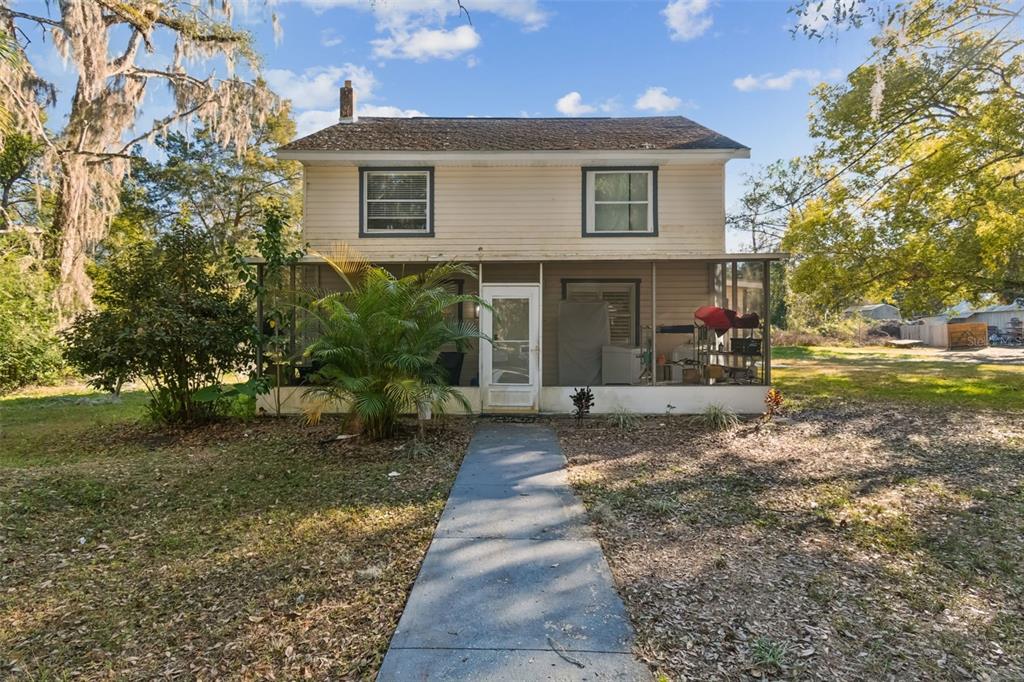 A two-story house with light siding, a screened-in front porch, and a concrete walkway — 19222 FORT DADE AVENUE, BROOKSVILLE, FL