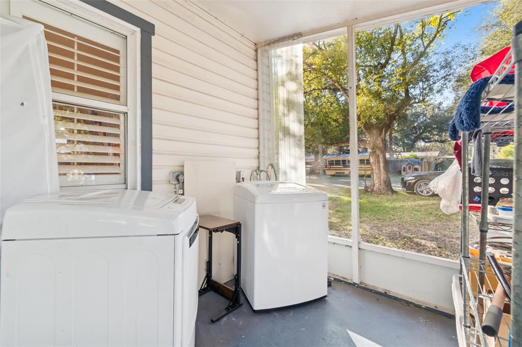 A screened-in porch contains two white washing machines and a small folding table — 19222 FORT DADE AVENUE, BROOKSVILLE, FL