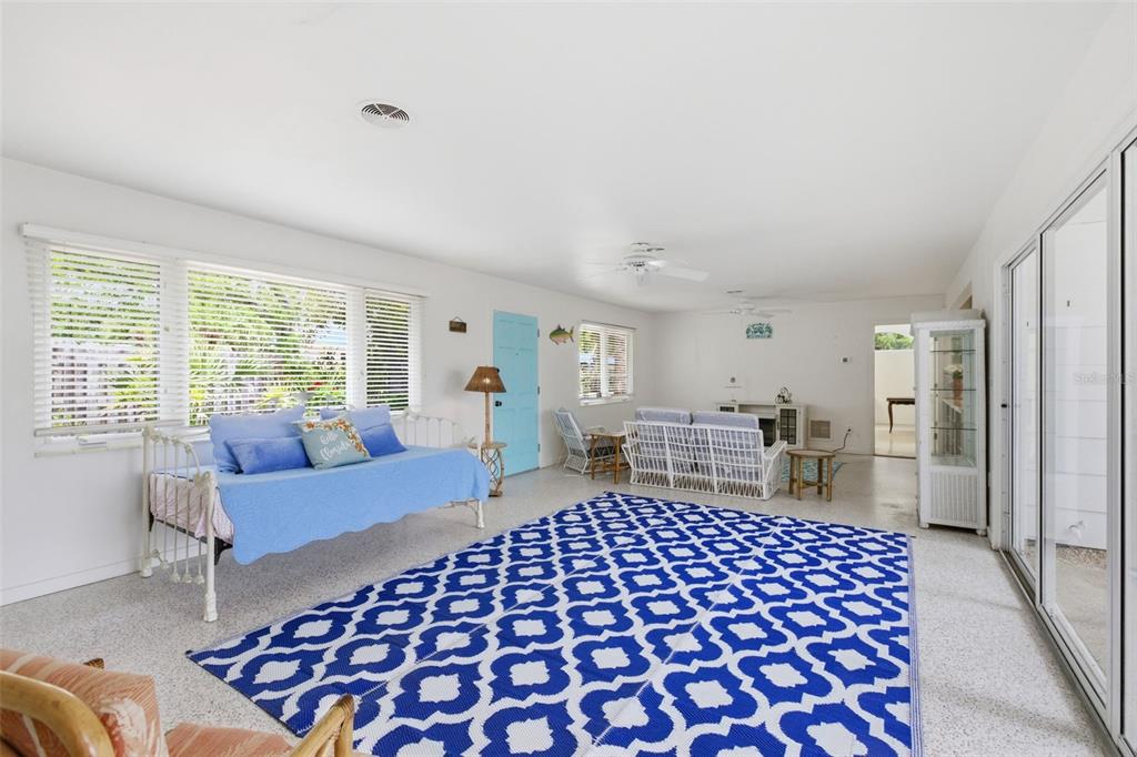 A bright, open-concept living room features a blue daybed, patterned area rug, and sliding doors — 528 RALPH STREET, SARASOTA, FL
