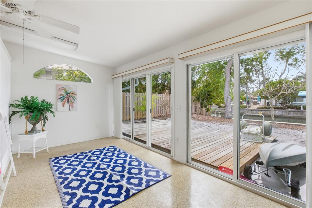A sunroom with a blue patterned rug, white walls, and sliding glass doors to a deck — 528 RALPH STREET, SARASOTA, FL