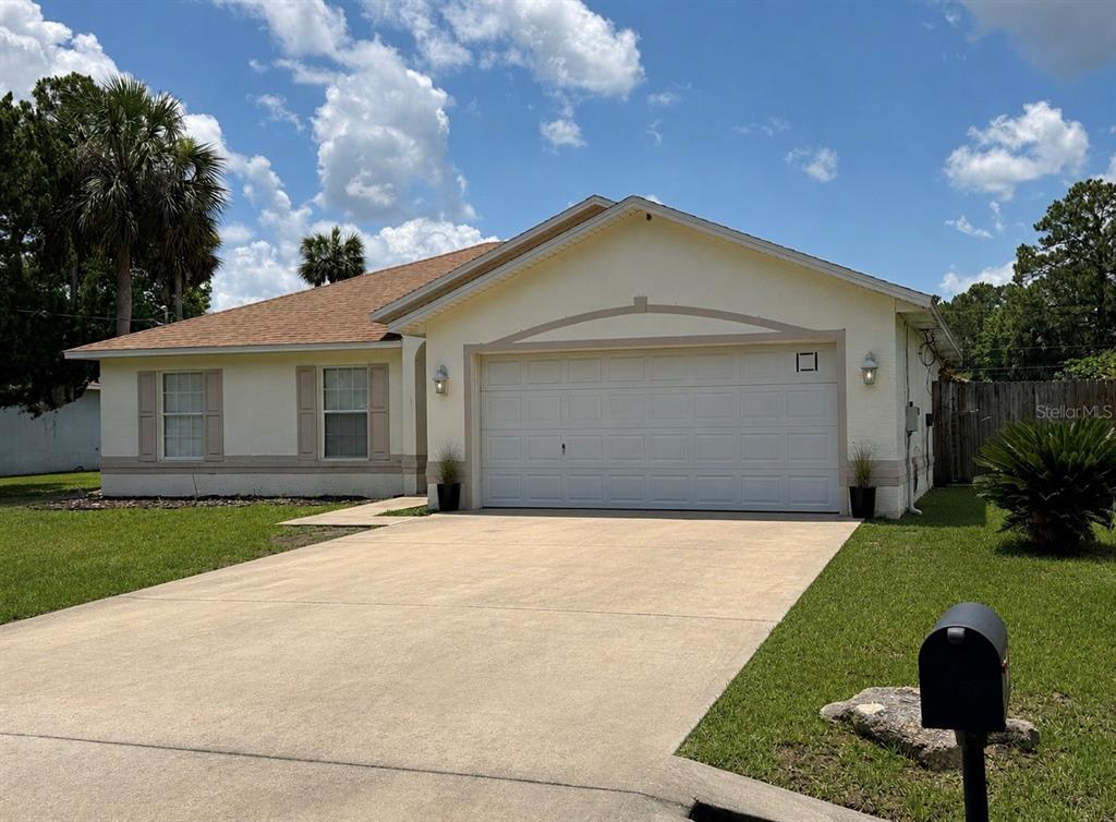 A single-story house with a beige stucco exterior, a two-car garage, and a concrete driveway — 36 PORT ROYAL DRIVE, PALM COAST, FL
