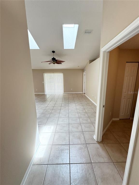 A tiled living area features a vaulted ceiling with skylights, a ceiling fan, and sliding doors — 36 PORT ROYAL DRIVE, PALM COAST, FL
