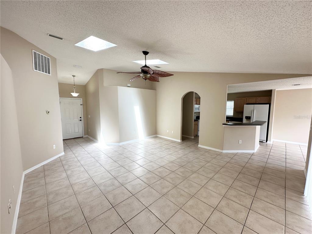 A spacious living area features beige tile flooring, vaulted ceilings with skylights, and an open kitchen — 36 PORT ROYAL DRIVE, PALM COAST, FL